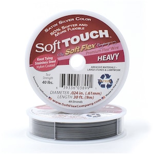 May include: A spool of silver Soft Touch Premium Flex Wire, labeled "Heavy" and "Abrasive Materials - Large Stones & Lampwork". The spool is 30 feet long and has a diameter of 0.024 inches. It is made in the USA.