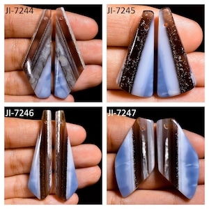 May include: Four pairs of polished, elongated gemstone pendants labeled JI-7244, JI-7245, JI-7246, and JI-7247. Each piece features a distinct banded pattern with alternating stripes of translucent light blue and dark brown, with a small hole at the top.