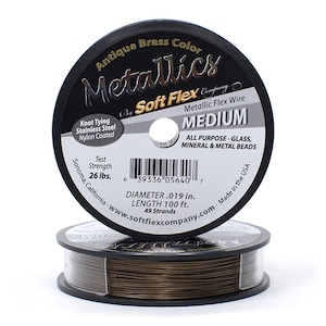 Op de afbeelding: Een spoel met Soft Flex Metallic Flex Wire in antieke messingkleur, Medium, 100 voet lang, 0,019 inch diameter, 49 strengen, voor alle soorten glas-, mineraal- en metalen kralen. De spoel is gelabeld met "Knot Tying Stainless Steel Nylon Coated" en "Test Strength 26 lbs."