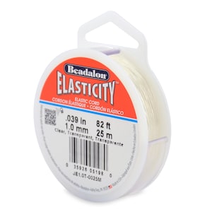 Op de afbeelding: Een spoel transparant Beadalon Elasticity elastisch koord. Het etiket toont: .039 in, 82 ft, 1,0 mm, 25 m. De spoel is wit met een rood en wit etiket.