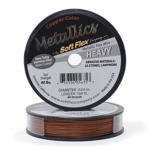 May include: A spool of copper colored Soft Flex Metallics Heavy wire. The spool is labeled with the brand name, product name, and details like test strength, diameter, length, and strands. The label also states that the wire is made in the USA and is ideal for abrasive materials, large stones, and lampwork.