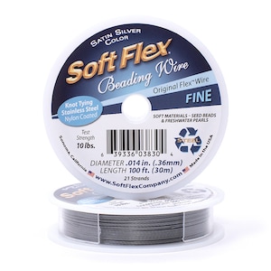 Op de afbeelding: Een spoel Soft Flex kralendraad in satijn zilver. De spoel is gelabeld "Soft Flex Beading Wire Original Flex Wire Fine" en heeft een treksterkte van 10 lbs. De draad is 0,36 mm in diameter en 30 meter lang. Het is gemaakt in de VS.