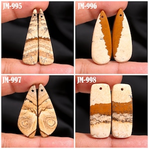 May include: Four pairs of gemstone pendants in various shapes. Each pendant is a mix of beige, brown, and white tones. The pendants are labeled JM-995, JM-996, JM-997, and JM-998. Each pendant has a small hole at the top for stringing.