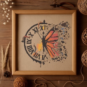 Peut inclure: Un motif de point de croix encadré représentant un cadran d'horloge avec des chiffres romains et un papillon aux ailes orange, jaunes et noires. Le papillon est partiellement brisé, créant un effet fragmenté.