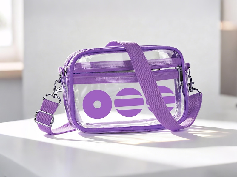 May include: A clear, purple crossbody bag with an adjustable strap. The bag has a purple zip and a design of purple circles and stripes. It features silver-coloured metal hardware.