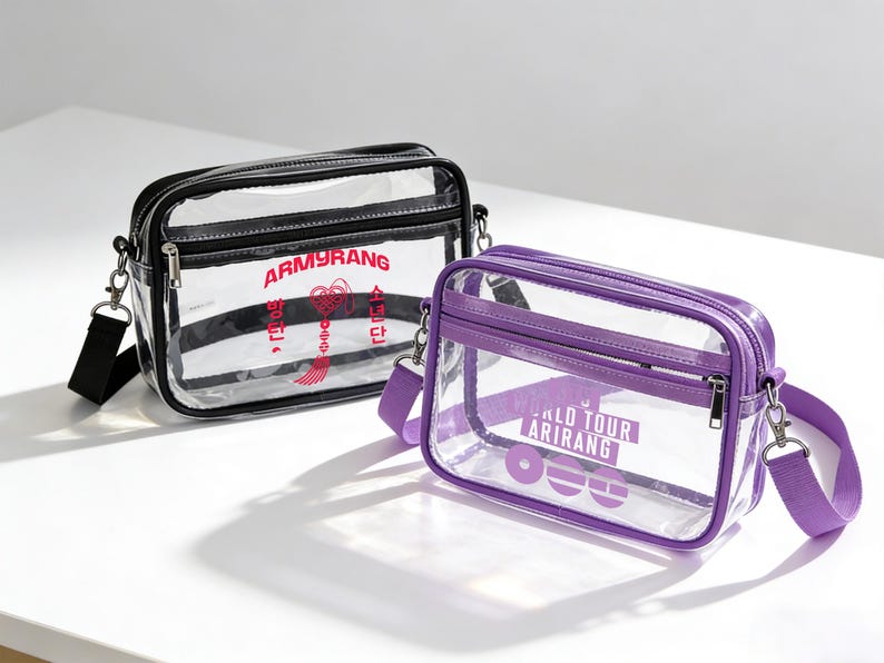 May include: Two transparent crossbody bags with black and purple trim. One bag has black straps and red text reading "ARMYRANG". The other has purple straps and white text: "WORLD TOUR ARIRANG".