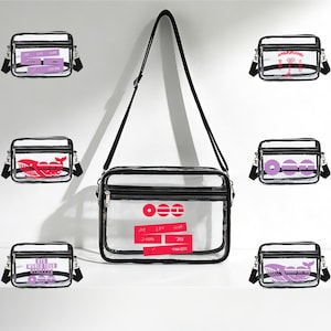 May include: Transparent crossbody bag with black trim and strap. The bag contains various designs, including a red whale, purple text, and red circles. The bag is displayed on a white surface.
