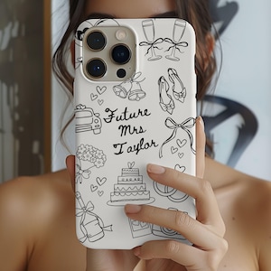 May include: White phone case featuring black line drawings of wedding symbols, such as champagne glasses, bells, a car, a cake, and the words "Future Mrs Taylor."