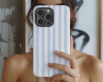 Peut inclure: Coque de smartphone à rayures verticales blanches et bleu clair. Le boîtier comporte un module caméra noir avec trois lentilles. Le téléphone est tenu devant une personne.