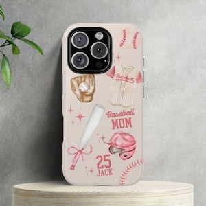 Puede incluir: Una funda para iPhone rosa y blanca con temática de béisbol. La funda presenta un guante de béisbol, un bate, una pelota de béisbol y una camiseta de béisbol. El texto "Baseball Mom" y "25 Jack" está impreso en la funda.