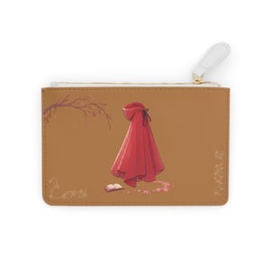 Könnte beinhalten: Braune Clutch mit einer Illustration eines roten Kapuzenmantels. Das Bild zeigt einen roten Umhang, ein offenes Buch und florale Akzente. Die Clutch hat einen weißen Reißverschlussanhänger und einen goldfarbenen Reißverschluss.