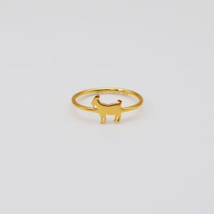 Peut inclure: Une bague dorée ornée d'une silhouette de chèvre. La bague présente un anneau fin et un petit charm en forme de chèvre. L'ensemble est présenté sur un fond blanc uni, mettant en valeur le design du bijou.