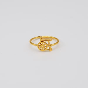 May include: A gold ring with a cannon-shaped emblem. The ring has a slender band and a detailed cannon design, possibly a sports-related symbol. The ring is displayed on a plain white background.