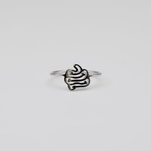 Puede incluir: Un anillo de plata con un diseño abstracto único. El anillo presenta una forma arremolinada rellena de negro en el centro, sobre una banda brillante y pulida. El diseño es moderno y llamativo, adecuado para el uso diario.