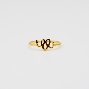 May include: A gold snake ring with a simple design. The ring is made of a thin band of metal and features a stylized snake design.