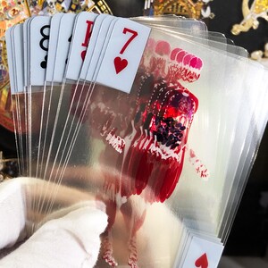 Image of Transparent Skeleton Playing Cards stacked in a neat pile next to a poker chip set and magician’s wand, conveying their use as a functional magic trick deck or science-themed poker night upgrade, combining education with entertainment and unique gifting potential.