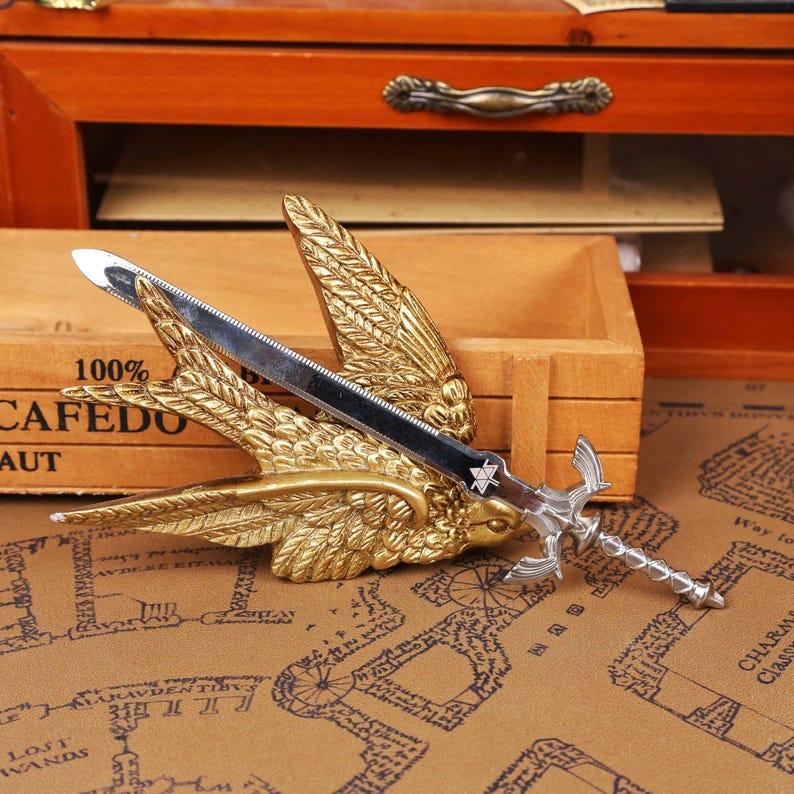 Zelda Master Sword Letter Opener with Triforce stand displayed on a gamer’s desk, showcasing its premium metal build and intricate hilt design, perfect for Zelda fans, TOTK and BOTW collectors, and fantasy lovers looking for a functional and decorative desk accessory. This high-quality zinc alloy sword replica doubles as a collectible display and practical envelope opener, making it ideal for Christmas gamer gifts, stocking stuffers, Halloween decorations, and unique holiday season gifts on Etsy