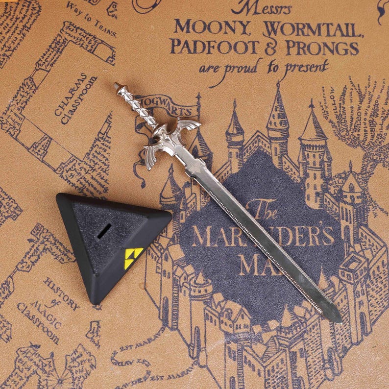 May include: A silver sword-shaped letter opener and a black triangular object with a yellow symbol. The items are on a map-like background with text including "Hogwarts" and "The Marauder's Map".