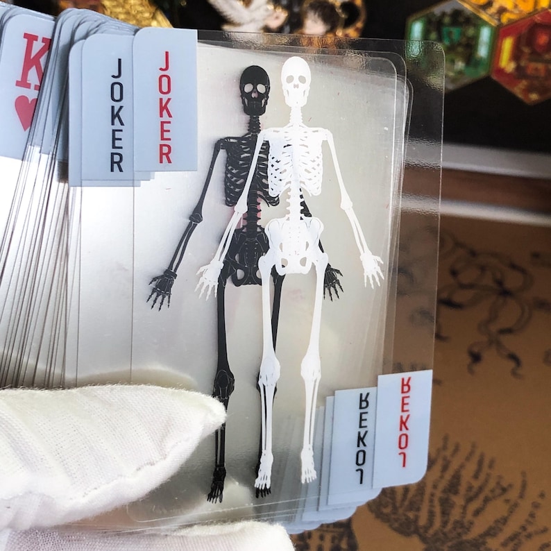 Top-down view of the full Transparent Skeleton Playing Card deck spread across a black surface, emphasizing the layered skeletal structure when arranged in order, offering a visually striking experience for science lovers, collectors, or as a creative gift for medical professionals and card game fans.