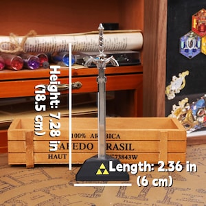 May include: A silver-colored decorative sword, 7.28 inches (18.5 cm) tall, with a black base and a yellow triangle emblem. The sword's length is 2.36 inches (6 cm). The background includes a wooden box and various decorative items.