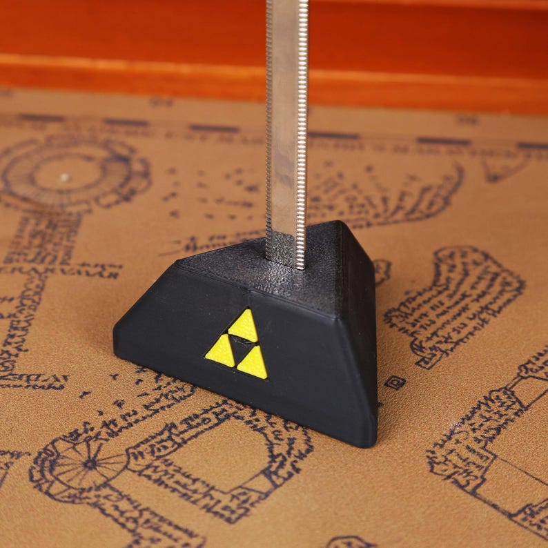 Close-up view of the Legend of Zelda Master Sword Letter Opener highlighting the detailed Triforce engraving, metallic shine, and durable construction. Perfect for gaming room decor, geek office accessories, and fantasy-themed holiday decorations. An excellent Zelda-themed gift idea for men, women, or teens who love video games, making it one of the best-selling Christmas gamer gifts and unique collectible sword items on the Etsy platform.