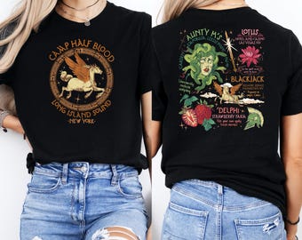 May include: Black t-shirt featuring a circular design with a winged horse and the text "CAMP HALF BLOOD LONG ISLAND SOUND NEW YORK." The back of the shirt has various graphics and text including "AUNTY M'S" and "DELPHI STRAWBERRY FARM."