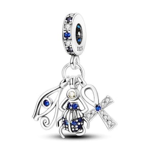 May include: Silver charm with an Egyptian theme. It features a scarab beetle, an eye of Horus, and an ankh, all adorned with blue and clear cubic zirconia stones. The charm is marked with "S925" on the back.