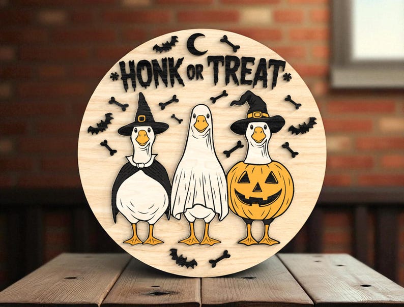 Puede incluir: Decoraci&oacute;n redonda de Halloween de madera con tres gansos disfrazados. Un ganso es una bruja, otro es un fantasma y otro es una calabaza. Las palabras "HONK OR TREAT" est&aacute;n en la parte superior, con murci&eacute;lagos y huesos alrededor.