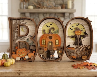 Könnte beinhalten: Ein dreiteiliges dekoratives Holzschild mit der Aufschrift BOO, bestehend aus geschichteten Ausschnitten von Kürbissen, einem Geist, einer Vogelscheuche, Fledermäusen und Bäumen in Orange-, Braun- und Cremetönen.
