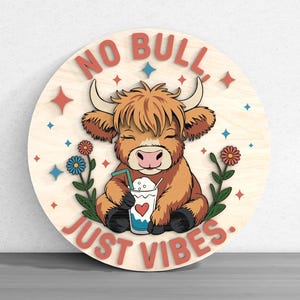 May include: A round wooden sign with a cartoon Highland cow holding a drink with a heart on it. The sign reads "NO BULL JUST VIBES" in red letters. The cow is brown and orange, with flowers and stars around it.