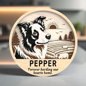 以下が含まれることがあります： 黒と白のボーダーコリー犬が描かれた丸い木製サイン。名前は「PEPPER」で、羊、木、夕焼けの牧歌的なシーンが描かれています。「Forever herding our hearts home」というテキストがあります。