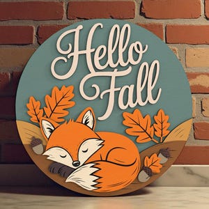 Może przedstawiać: Okrągły drewniany znak z napisem "Hello Fall" w kolorze białym. Przedstawia śpiącego pomarańczowego lisa, pomarańczowe liście i żołędzie na tle w kolorze morskim. Dekoracja w stylu jesiennym.