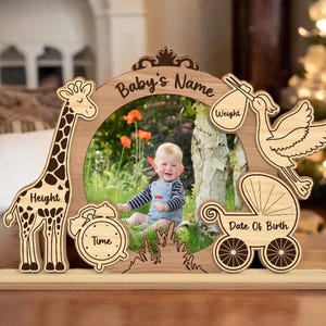 Op de afbeelding: Houten fotolijst met een giraffe, een ooievaar en een kinderwagen. De lijst heeft ruimte voor een foto, de naam van de baby, het gewicht, de lengte, de tijd en de geboortedatum.