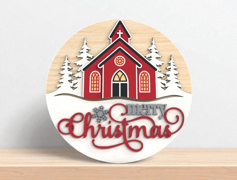Puede incluir: Decoraci&oacute;n navide&ntilde;a redonda de madera con una iglesia roja, tejado negro y nieve blanca. Las palabras "merry Christmas" est&aacute;n escritas en rojo y gris. Los &aacute;rboles blancos flanquean la iglesia.