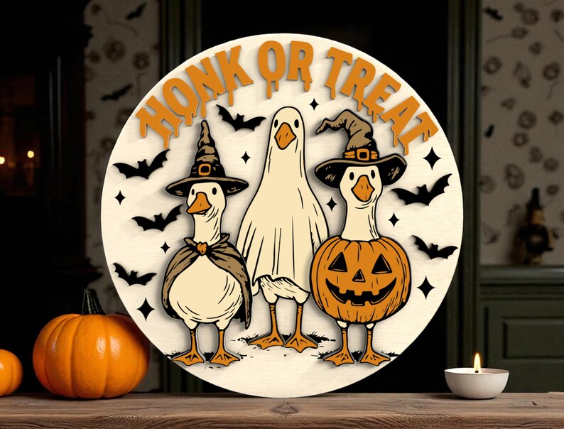 Puede incluir: Decoraci&oacute;n redonda de Halloween de madera con tres gansos disfrazados. Uno lleva un sombrero de bruja y una capa, otro es un fantasma y el tercero es una calabaza. Las palabras "HONK OR TREAT" est&aacute;n en la parte superior.