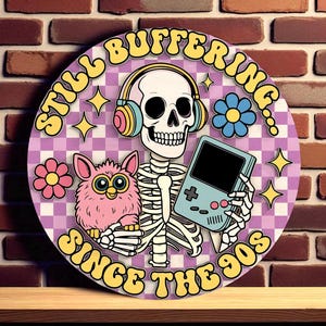 Op de afbeelding: Rond bord met een retro design met een skelet met een koptelefoon en een draagbare gameconsole en een roze Furby. Het bord heeft de tekst "Still Buffering Since the 90s" in het geel.