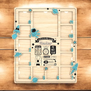 Puede incluir: Marco de fotos de madera para hitos del bebé con decoraciones temáticas espaciales. Cuenta con recortes para fotos, cohetes azules, planetas y estrellas. Incluye el nombre "Harley" y detalles de nacimiento: 3,6 kg, 50,8 cm.