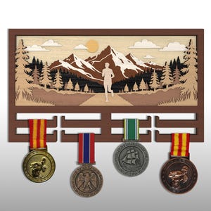 May include: Wooden medal display with a mountain and runner silhouette design. The display has four hooks holding medals with colorful ribbons. The background features a mountain scene with trees, clouds, and a sun.