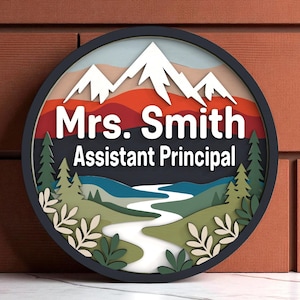 May include: A circular, layered wooden sign depicting a mountain and river scene. The sign displays the text "Mrs. Smith Assistant Principal" in white lettering against a dark backdrop, enclosed by a black border.