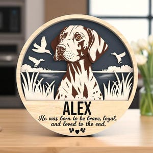 Könnte beinhalten: Runde Holzplakette mit einem Hundeporträt und dem Namen "ALEX". Das Design beinhaltet eine Hundeillustration, Vögel und den Text "He was born to be brave, loyal, and loved to the end." Die Plakette ist ein dekorativer Artikel.