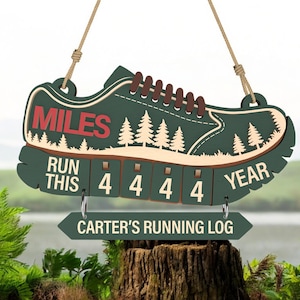 May include: A wooden running shoe-shaped sign in shades of green, brown, and beige, with the words "MILES" and "RUN THIS YEAR" in red and white. The sign includes a running log with the text "CARTER'S RUNNING LOG".