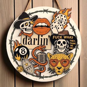 Könnte beinhalten: Runder Holzschild mit verschiedenen Illustrationen im Tattoo-Stil. Es zeigt einen Totenkopf mit Cowboyhut, brennende Würfel, eine Schlange und das Wort "darlin". Das Schild ist mit Stacheldraht und einem Seil zum Aufhängen verziert.