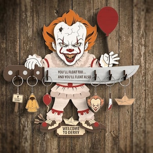 May include: A wooden key holder featuring a menacing clown design with the text "YOU'LL FLOAT TOO... AND YOU'LL FLOAT ALSO." Includes keychains with related imagery. The clown has orange hair and a red balloon.