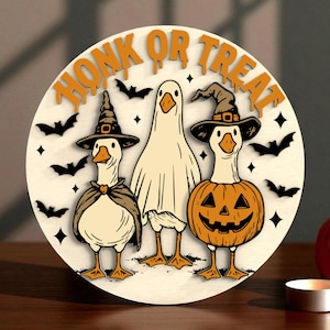 Puede incluir: Decoraci&oacute;n redonda de Halloween de madera con tres gansos de dibujos animados. Uno est&aacute; disfrazado de fantasma, otro lleva un sombrero de bruja y una capa, y el tercero est&aacute; con un disfraz de calabaza. Las palabras "HONK OR TREAT" est&aacute;n en la parte superior, con murci&eacute;lagos y estrellas.