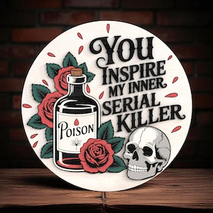 May include: Circular wooden sign featuring the phrase "You Inspire My Inner Serial Killer." The design incorporates a poison bottle, roses, and a skull. The bottle is black with a white "Poison" label.