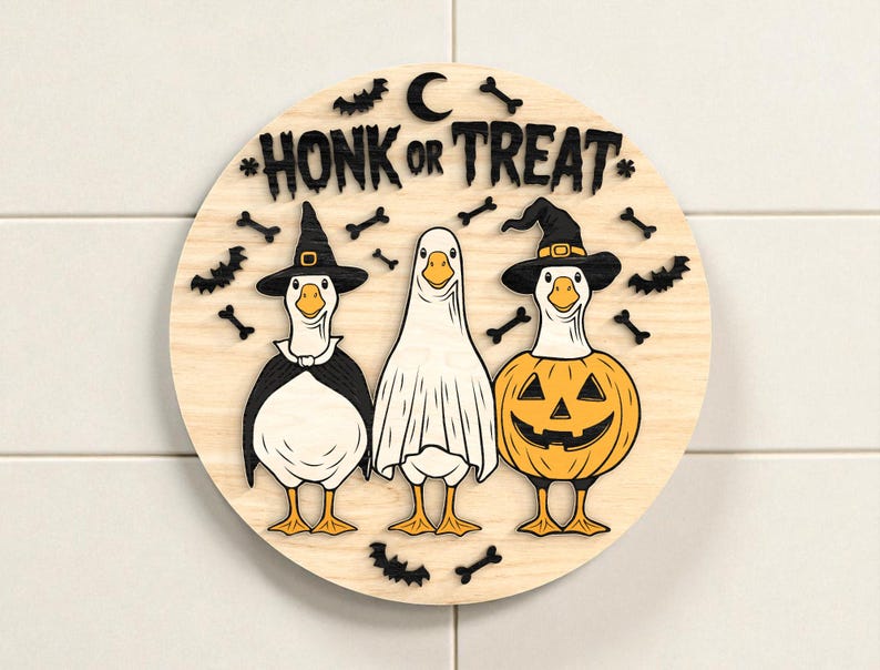 Puede incluir: Decoraci&oacute;n redonda de Halloween de madera con tres gansos disfrazados. Un ganso es una bruja, otro un fantasma y otro una calabaza. Las palabras "HONK OR TREAT" est&aacute;n en la parte superior, con murci&eacute;lagos y huesos.