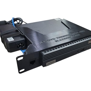 May include: A black Lenovo ThinkCentre computer with a power supply and a network port. The text "LENOVO THINKCENTRE BLAZINGCOM" is printed on the top of the computer. The computer is mounted in a rack.