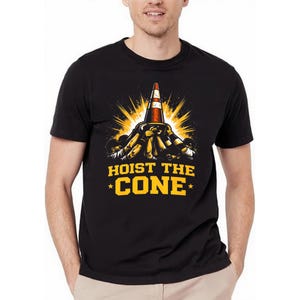 May include: Black t-shirt featuring a graphic of a traffic cone being lifted by multiple hands, with a yellow light burst. The text "HOIST THE CONE" is in yellow, with stars on either side.