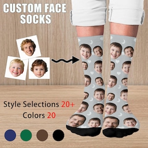 May include: Grey socks featuring custom faces. The socks are patterned with faces, moons, and hearts. The text "CUSTOM FACE SOCKS" is at the top. The text "Style Selections 20+ Colors 20" is at the bottom.