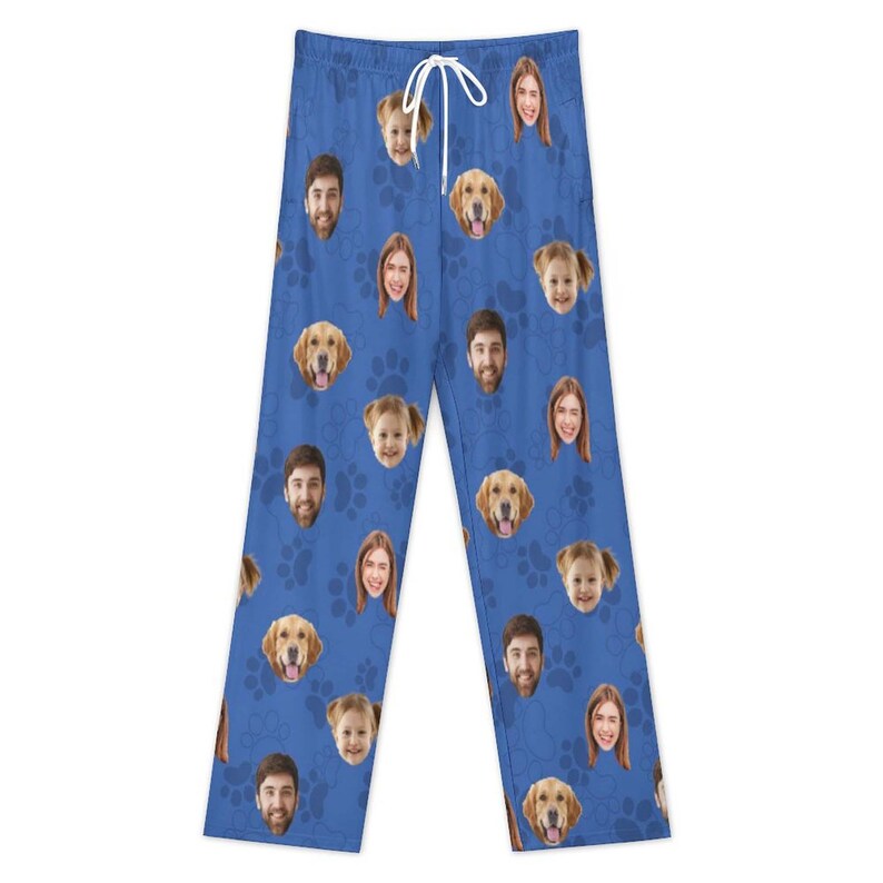 May include: Blue pajama pants with a white drawstring, featuring a pattern of faces and golden retriever dog faces. The design includes paw prints. The pajama pants are made of a soft material.